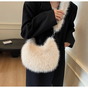 Sac bandoulière beige en fausse fourrure porté avec un manteau noir en laine pour l'hiver