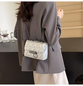 Detailed view of a silver quilted chain bag worn crossbody by a model in a minimal setting
