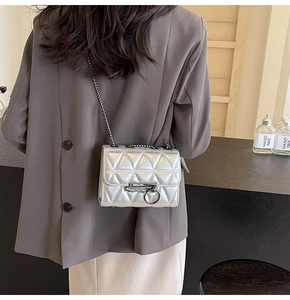 Detail of silver metallic crossbody bag with geometric quilting and metal chain strap