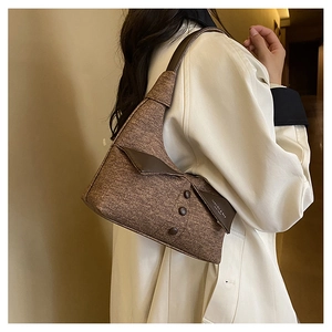 Détail du sac à bandoulière en tweed marron avec bordure en cuir et lettrage