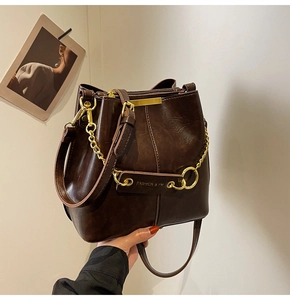 Detail of dark brown bucket bag with gold chain and Fashion & Yv lettering
