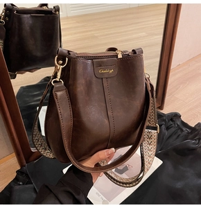 Detail of vintage brown bucket bag featuring wide jacquard strap and gold hardware