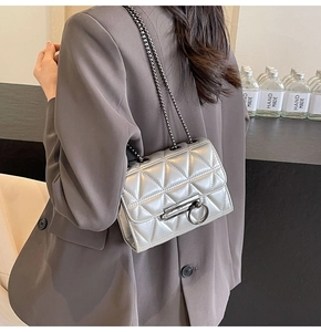 Silver quilted chain bag with round metal buckle shown on a stylish blazer outfit