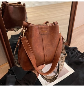 Detail view of brown vintage bucket bag with ethnic woven strap and gold metal hardware