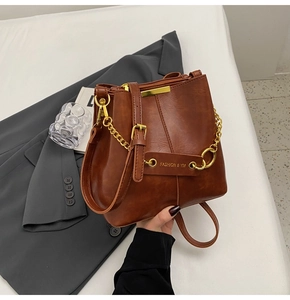 Detail of vintage brown bucket bag with gold metal buckle and leather shoulder strap