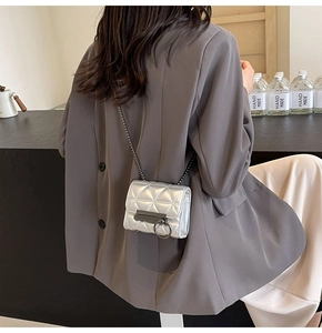Detail of silver quilted mini crossbody bag with metal chain strap on model back