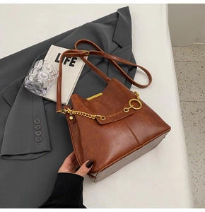 Macro detail of brown lychee leather bucket bag with gold chain and metal hardware
