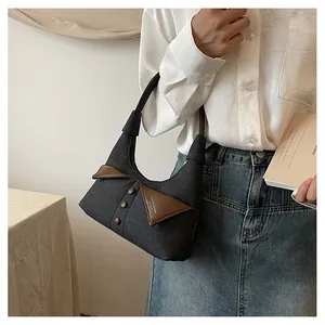 Détail du sac à bandoulière en denim gris avec garniture en cuir brun et boutons rétro