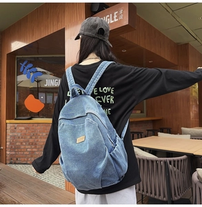 Close-up of blue denim backpack with a brown logo patch and durable shoulder straps