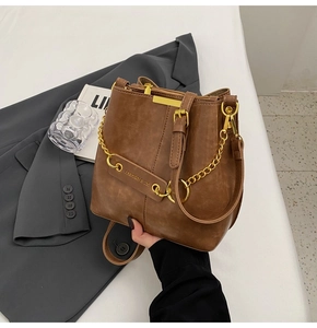 Detail of vintage brown bucket bag featuring gold chunky chain and buckle leather texture