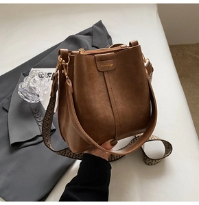 Close-up of vintage brown bucket bag featuring a woven strap and golden hardware