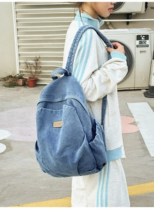 Detail of blue denim backpack side pocket and leather label on outdoor travel daypack