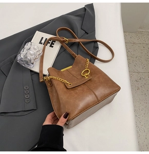 Detailed close-up of brown vintage bucket bag with gold chain and textured leather surface
