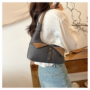 Détail du sac en tissu gris avec rabat en cuir marron et boutons décoratifs
