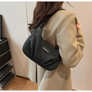 Close-up of black pleated underarm bag with Fashion metal logo and textured finish