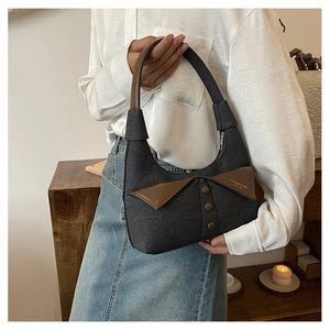 Détail du sac sous le bras en denim gris foncé avec col en cuir marron et boutons rétro