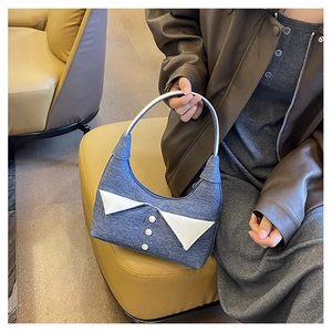 Détail du sac à bandoulière en denim bleu avec col blanc et boutons porté par un mannequin
