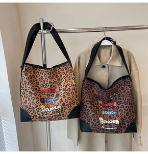 Detail of leopard print tote bags featuring cartoon dachshunds and reinforced leather corners