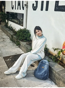 Detail of white sporty sweatshirt and track pants set with blue side stripes on sleeves