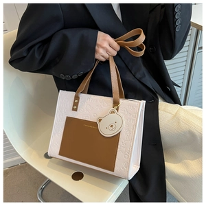 Detail der rosa geprägten Tragetasche mit brauner Ledertasche und süßem Bären-Anhänger