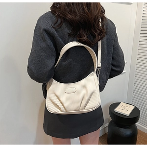 Detail of cream corduroy crescent bag showing vertical pleated texture and leather strap