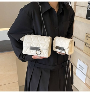 Detail view of white quilted chain bags with metal buckles and shoulder straps