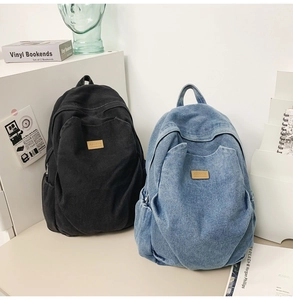 Close-up of high-capacity washed denim and black canvas backpacks for daily travel