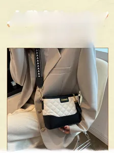 Detail of quilted bucket bag with gold logo and contrast black and white geometric strap
