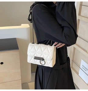 Detail of white quilted leather crossbody bag with metal chain strap on model