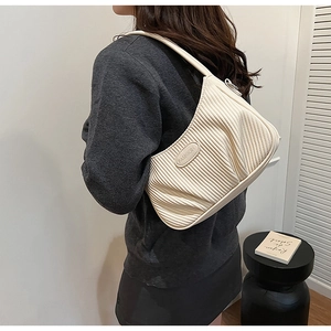 Detail of cream pleated shoulder bag showing wavy texture and Fashion logo emblem
