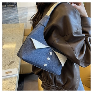 Détail du sac à bandoulière en denim bleu avec revers unique et boutons blancs élégants