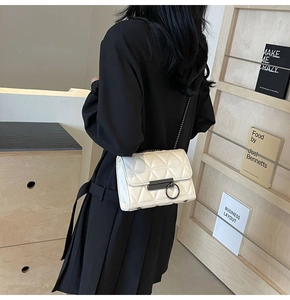 Detailed view of a white quilted chain bag with V-shaped stitching and metal buckle