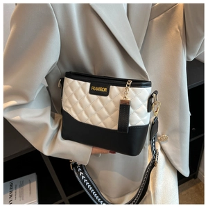 Détail du sac seau matelassé avec large bandoulière imprimée et accent de chaîne dorée