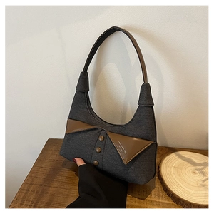 Détail du sac sous l'aisselle en toile gris foncé avec bordure en cuir marron et boutons