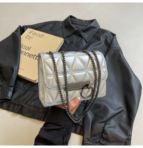 Detail of silver quilted shoulder bag with geometric patterns and dark metal chain strap
