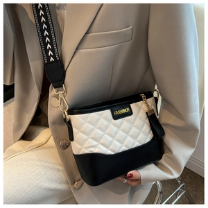 Détail du sac seau matelassé avec large bandoulière et logo en métal doré