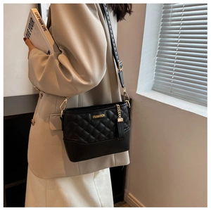 Gros plan du sac bandoulière matelassé noir avec logo doré et bandoulière à motifs