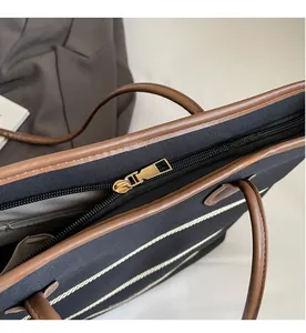 Detail of smooth gold zipper and texture on canvas tote bag with brown trim
