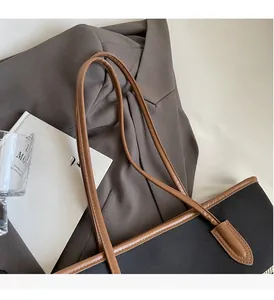 Detail of reinforced stitching and durable brown shoulder straps on black canvas tote bag