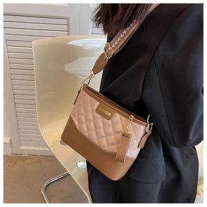 Détail du sac seau bicolore en cuir matelassé avec large bandoulière en jacquard