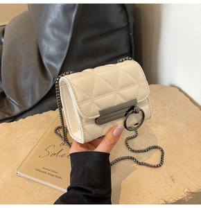 Close-up of beige quilted bag with gunmetal ring clasp on a vintage magazine
