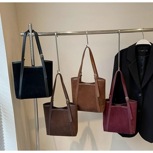 Detail view of four suede tote bags in various autumn colors with adjustable straps