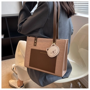 Detail der nude-rosa Tote Bag mit Bärenprägung und Kontrasttasche zum grauen Blazer-Outfit