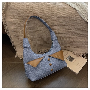 Détail du sac sous le bras en denim bleu avec col en cuir marron et boutons décoratifs