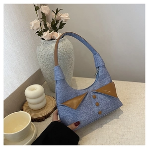 Détail du sac croissant en denim bleu clair avec col de chemise en cuir marron