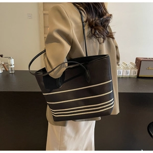 Side view of large black canvas tote bag with beige stripes and long shoulder straps