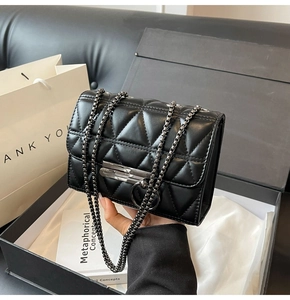 Detail of black quilted leather chain bag with metallic ring buckle in premium gift box