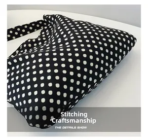 Detail of white polka dot pattern and precise stitching on black canvas tote bag