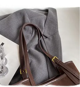Detail of adjustable leather strap and golden buckle on a brown suede tote bag