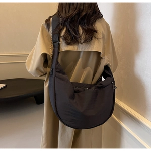 Rear view of a model wearing a minimalist black nylon crescent crossbody bag